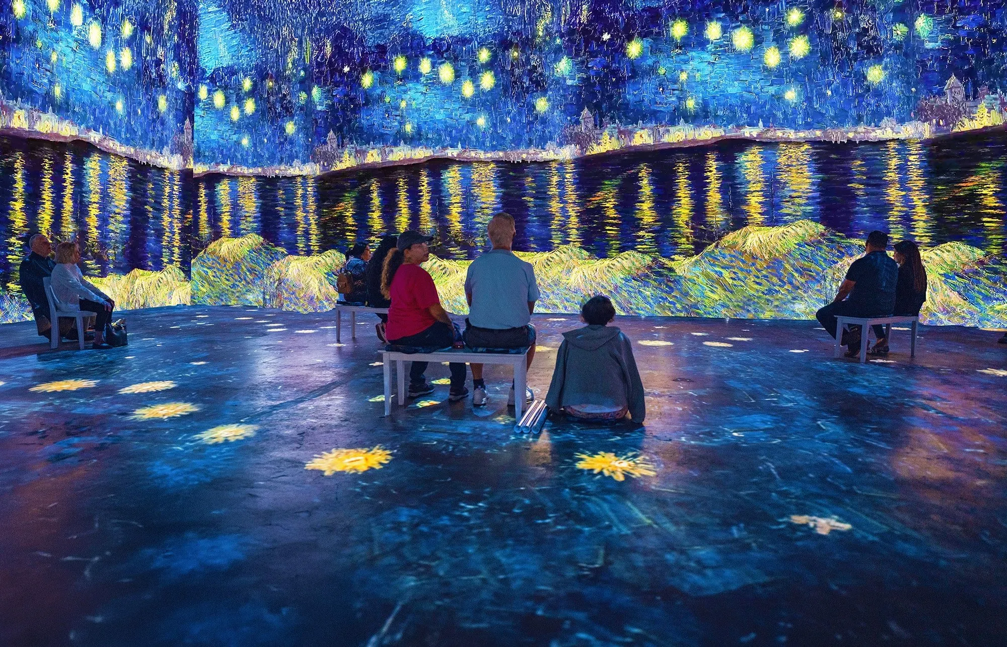 Visitors seated before a projected starry river scene